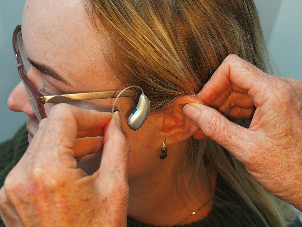 A woman is putting on her ear piece